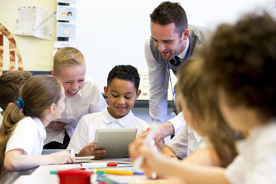 Teacher with students using notepad and laughing