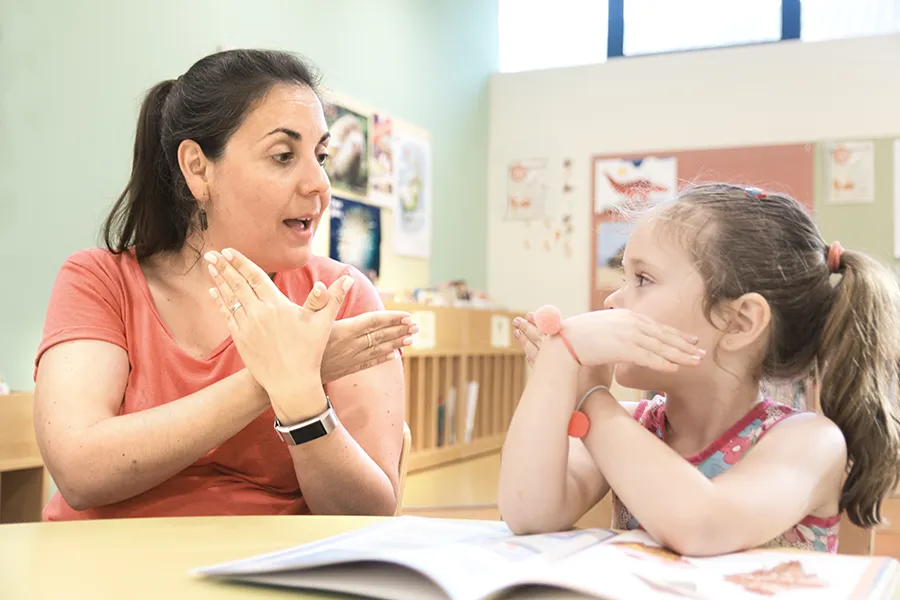 Teacher using sign language with a student in their classroom
